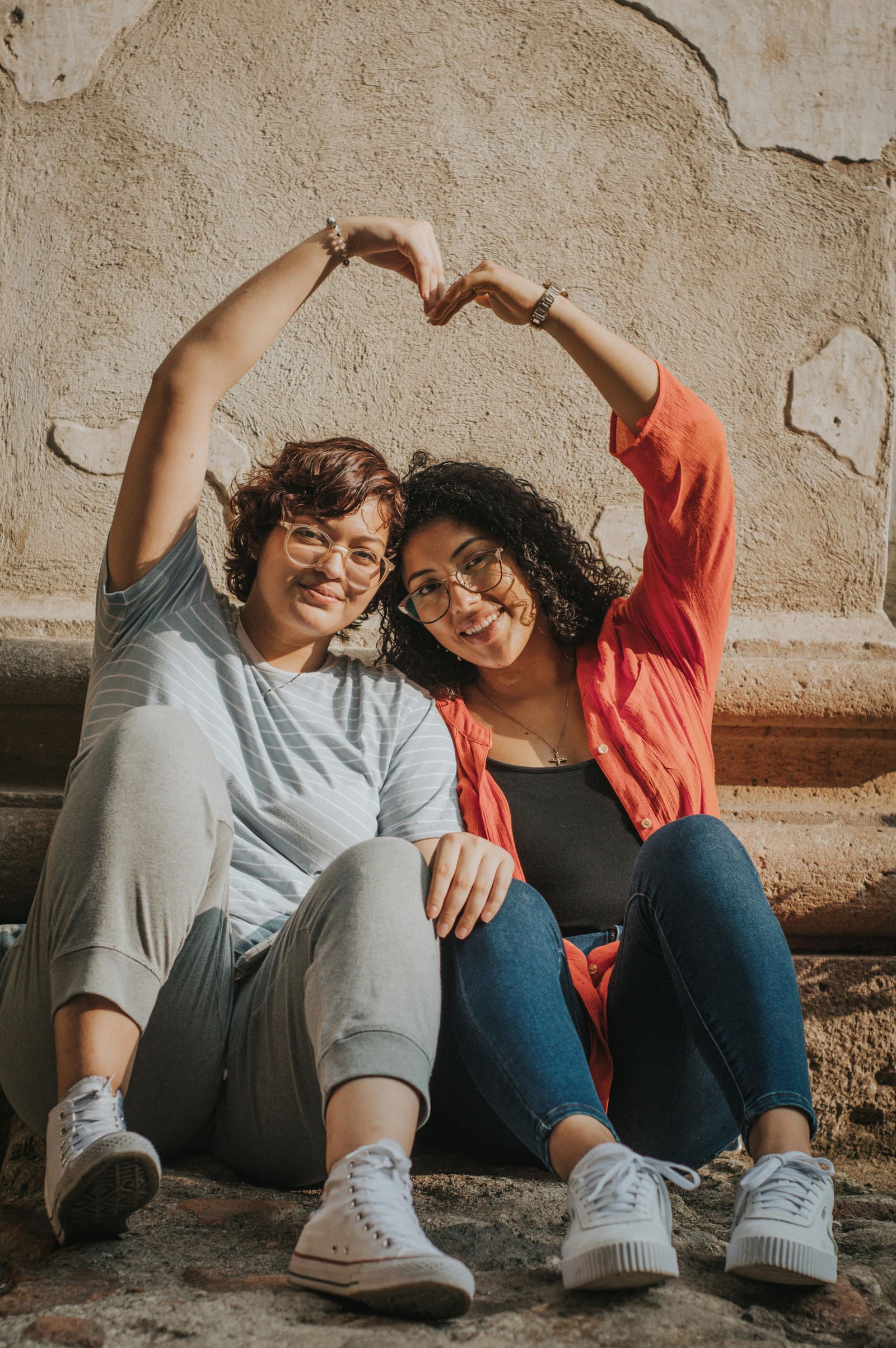 Two women forming a heart shape with their hands